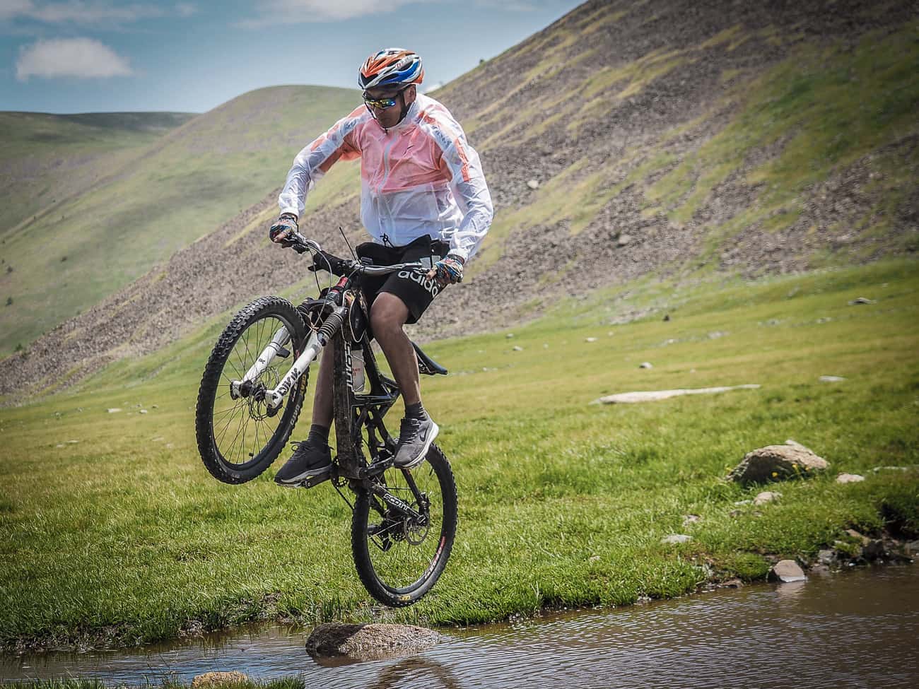 a Mongolian mountain biker jumping a stream 