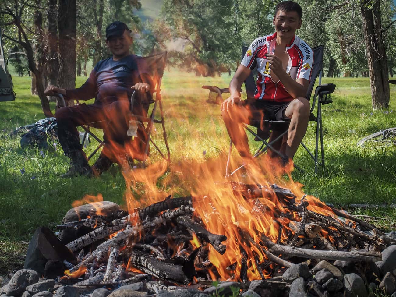Mongolian men by a camp fir on a cycling tour