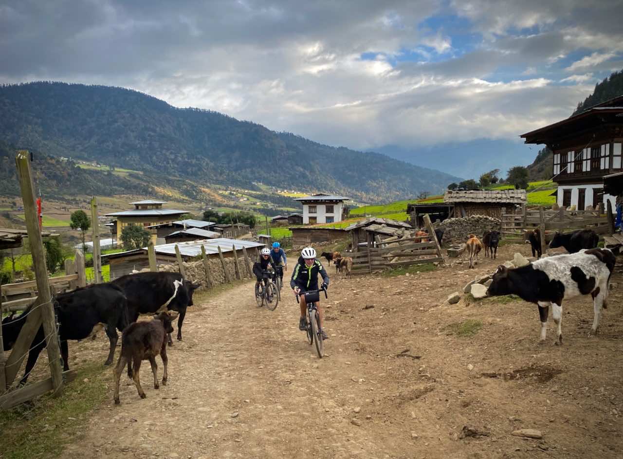 Gravel cyclists on holiday in Bhutan pass cowns in a small village on a gravel road.