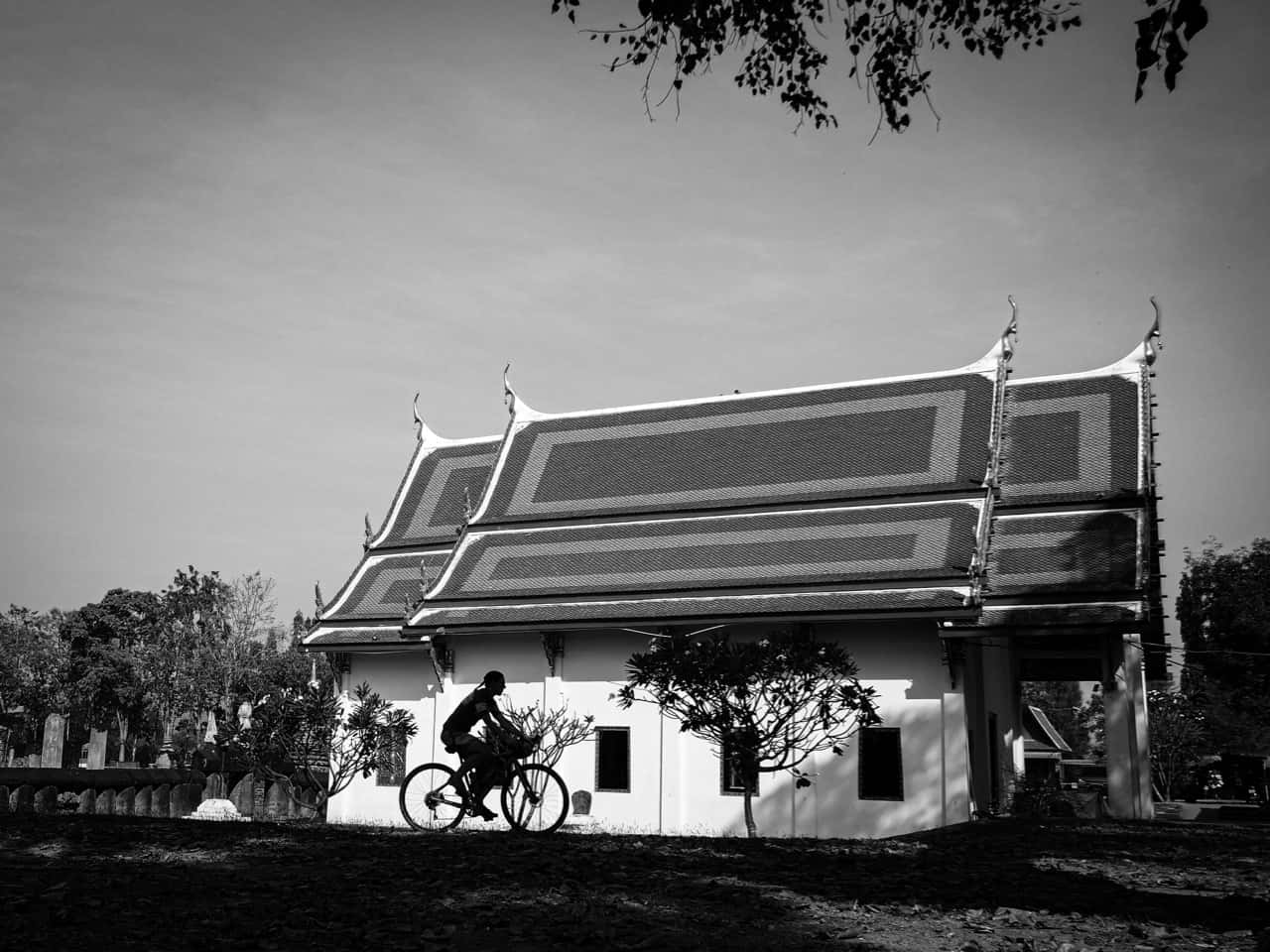 gravel cyclists passing old temple in Thailand black and white image
